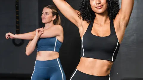 Two women in a gym wearing coordinating activewear sets