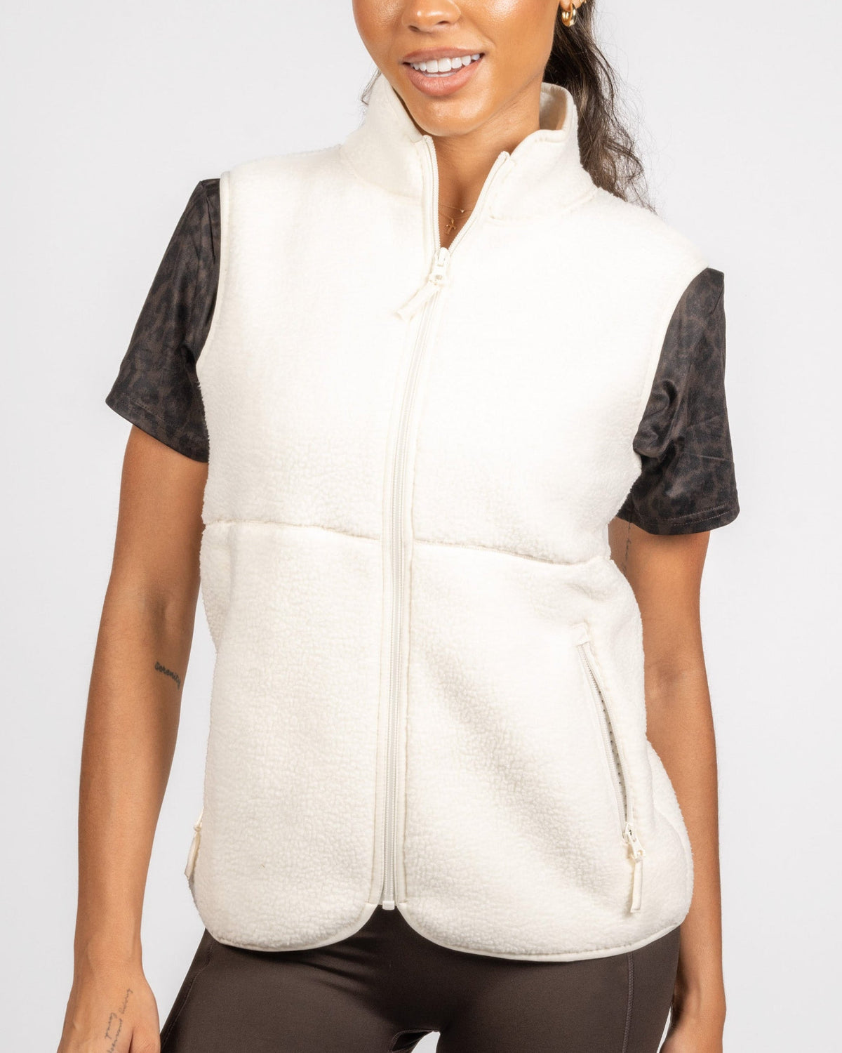 Woman wearing a white puffer vest over a black shirt on a white background